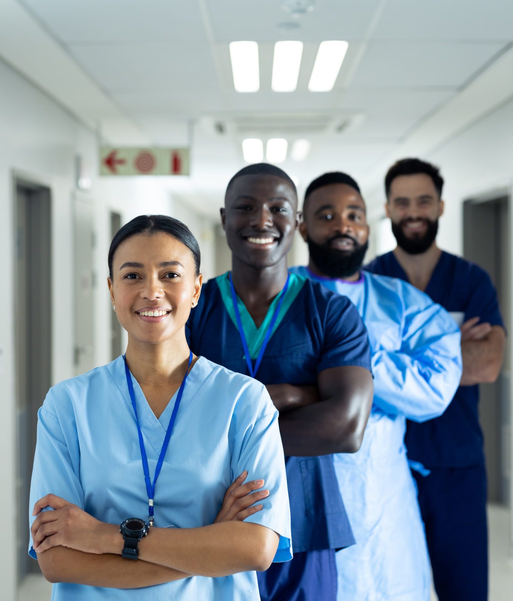 Vertical portrait of diverse group of smiling healthcare workers in line in corridor, copy space. Hospital, medical and healthcare services.