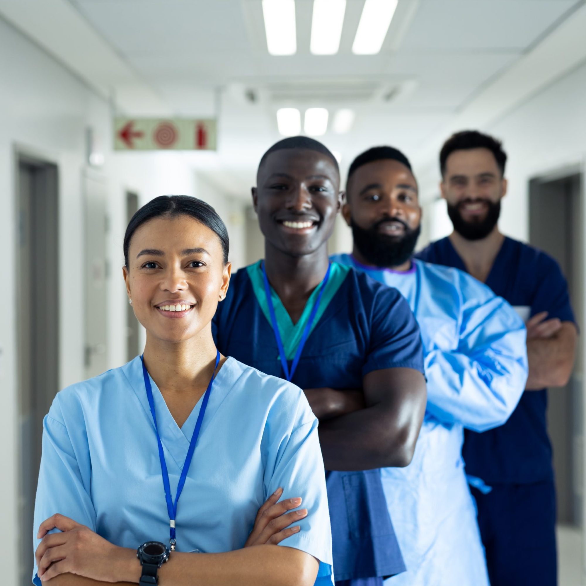 Vertical portrait of diverse group of smiling healthcare workers in line in corridor, copy space. Hospital, medical and healthcare services.